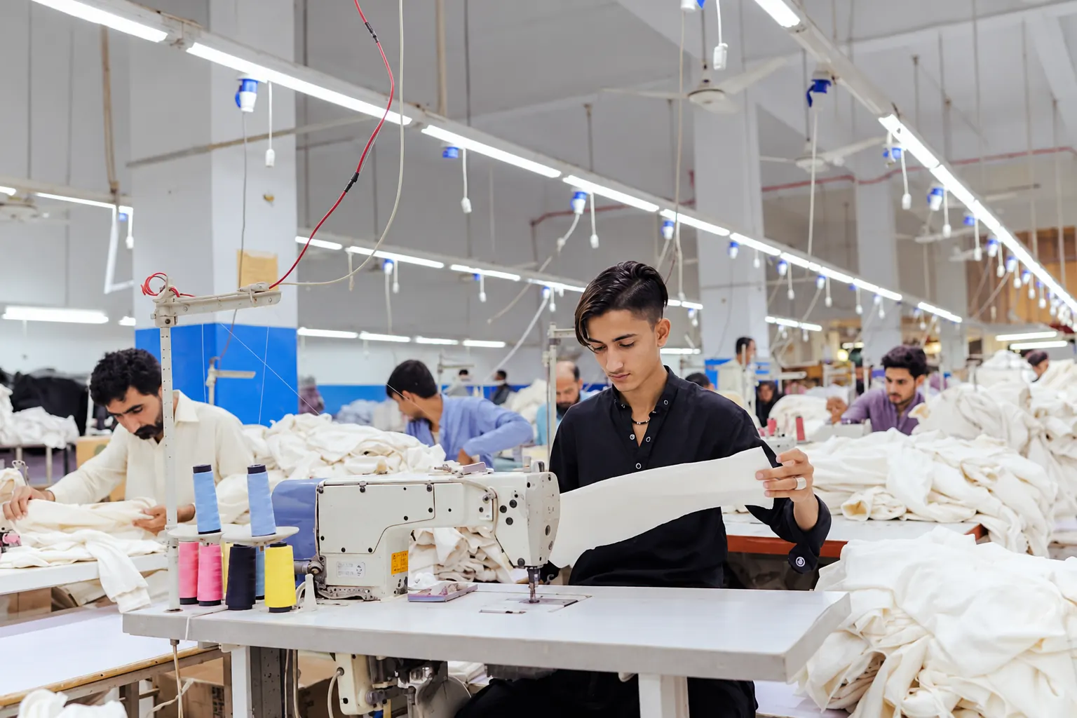 Sewing workstation Sewing machine operator handling white fabric in the stitching department.