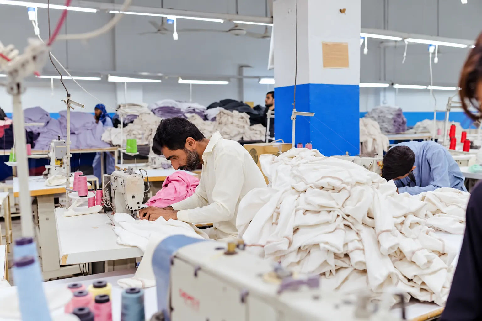 Stitching in progress Workers stitching textiles at industrial sewing machines.